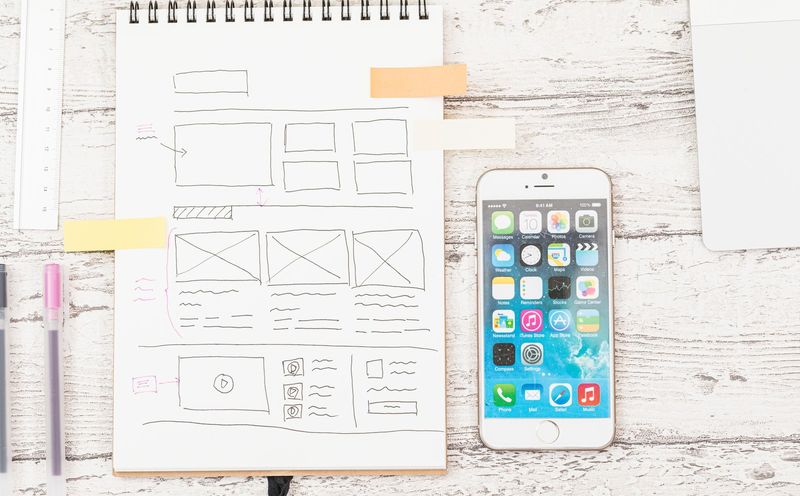 Webページの設計図を描いたノートとスマートフォン