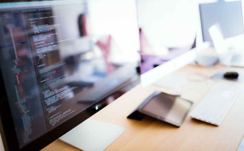コードが表示されたモニターのあるデスク